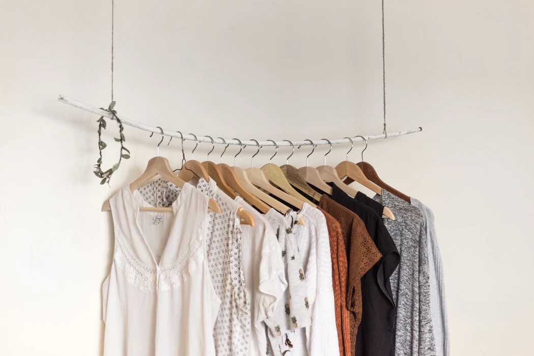 white brown and grey shirts hanging on a rack against a white wall